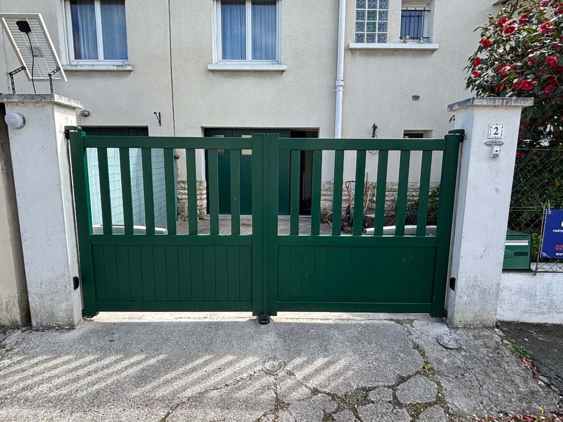 Portail vert à barreaudage devant une maison