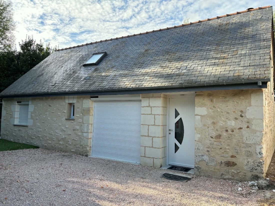 Longère en pierre avec porte de garage blanche