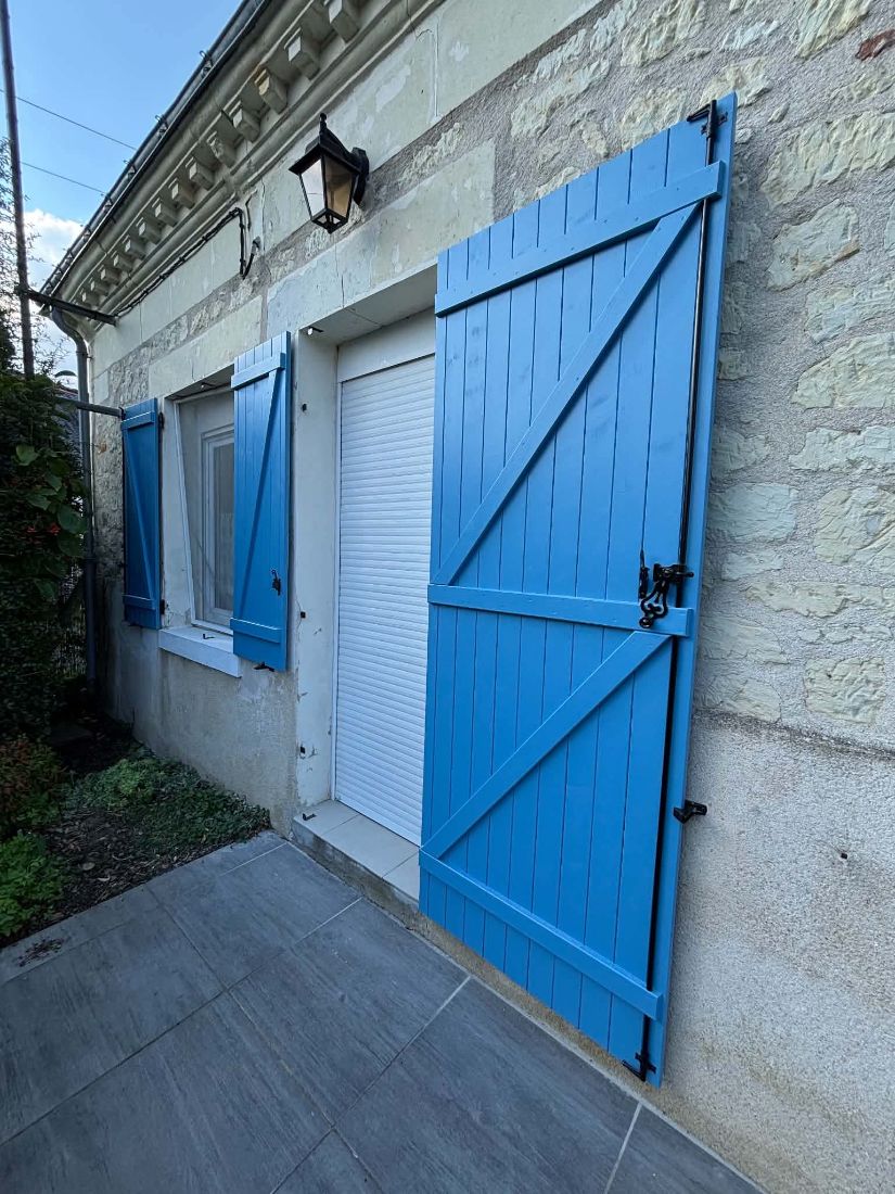 Volets battants bleus sur une façade en pierre