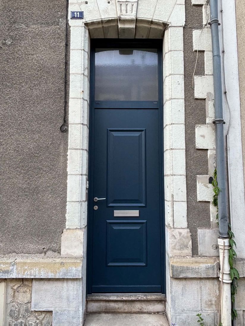 Porte d’entrée bleu marine à moulures dans un encadrement en pierre